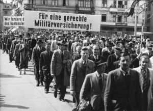 Labour Day parade, march with a banner: ‘For a Fair Military Insurance!’ Schweizerisches Sozialarchiv, Sozarch_F_5047-Fb-090.
